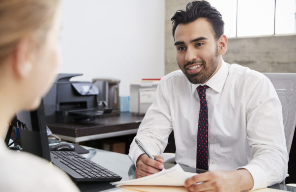 Young Hispanic male professional in meeting with woman in office