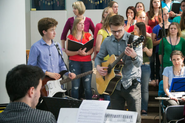 Two-males-with-guitars-with-people-standing-behind